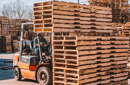 man moving stacks of pallets with a forklift